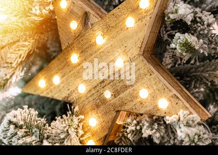 Stella decorativa in legno con lampade appese su rami di pino. Foto Stock