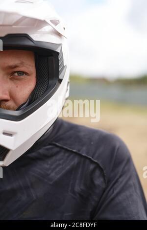 Ritratto di violento motociclista in casco e giacca in piedi all'aperto Foto Stock