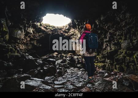 Donna viaggiatore esplorare il tunnel di lava in Islanda. Foto Stock