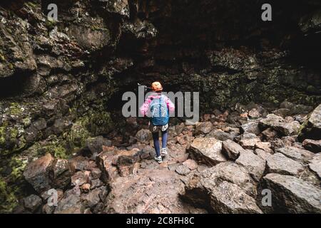 Donna viaggiatore esplorare il tunnel di lava in Islanda. Foto Stock