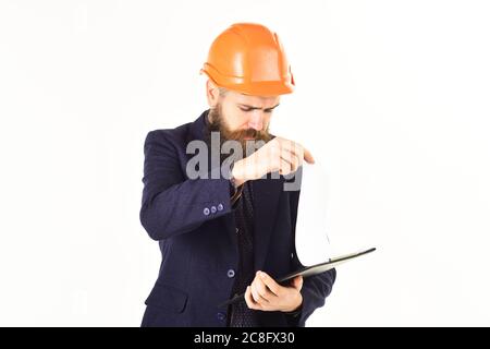 Supervisore con carte, casco e viso serio. L'ispettore conserva documenti e prende appunti. L'uomo con la bearded indossa un casco isolato su sfondo bianco. Ispezione, supervisione, progetto. Foto Stock