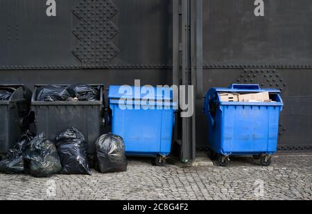 I dumpster in plastica in diversi colori a causa del riciclaggio. I contenitori dei rifiuti sono caricati e pieni di rifiuti, rifiuti e rifiuti Foto Stock