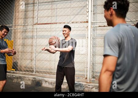 giovani uomini adulti asiatici che si divertono giocando con il basket all'aperto Foto Stock