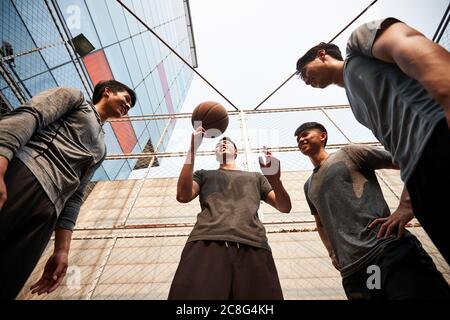 giovani uomini adulti asiatici che si divertono giocando con il basket all'aperto Foto Stock