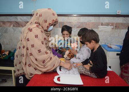 QUETTA, BALOCHISTAN, PAKISTAN. 24-2020 luglio: Un membro dell'organizzazione di donne di oggi (DUE Quetta) che guida i pazienti del bambino che giocano circa libro di colorazione Foto Stock