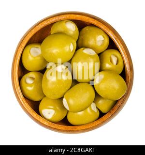 Olive verdi farcite con spicchi d'aglio in una ciotola di legno. Olive grandi, frutta di Olea europaea, farcite a mano con pezzi d'aglio sottaceto. Primo piano. Foto Stock