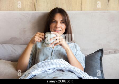 Buongiorno! Donna si svegliò a letto. Donna che beve caffè a letto Foto Stock