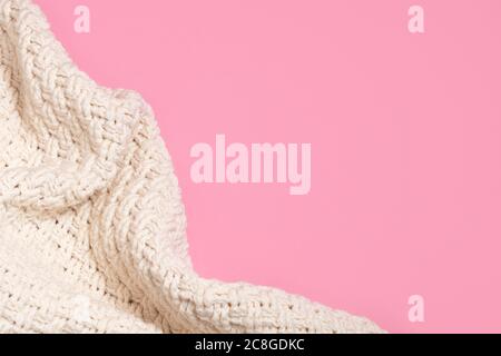 Confortevole coperta o pullover beige lavorato a maglia su sfondo rosa pastello con spazio per la copia Foto Stock