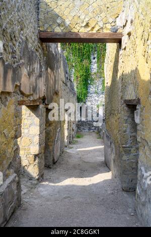 Una stretta strada tra gli edifici della città romana di Ercolano, parzialmente distrutta dall'eruzione del Vesuvio nel 79 d.C. Foto Stock