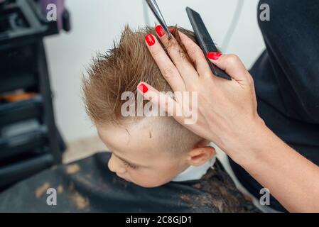 Primo piano foto delle mani di un barbiere che lavora con forbici per capelli Foto Stock