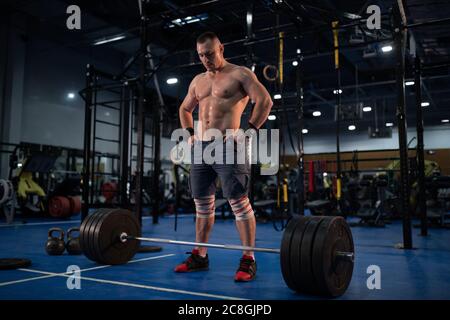 Atleta forte a tutta lunghezza con le mani in vita che si prepara a deadlift in palestra Foto Stock