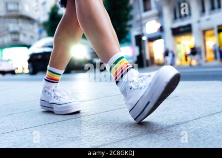 le gambe della donna che camminano lungo la strada con una macchina dentro lo sfondo Foto Stock