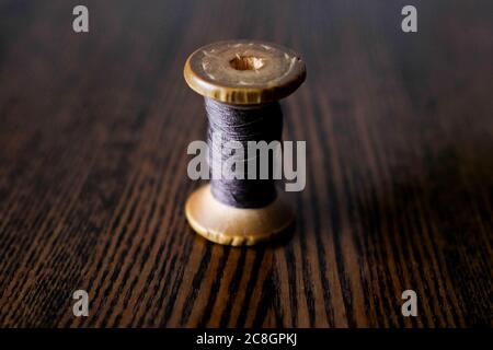 Rocchetto di legno di filo. Filo sottile viola. Sfondo scuro. Foto Stock