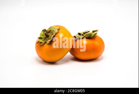 due persimmons arancioni mature che si appoggiano l'uno contro l'altro isolati su bianco Foto Stock