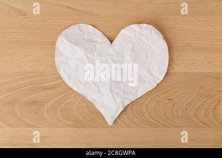 cuore di carta sminuzzata bianca su legno, concetto straziato Foto Stock