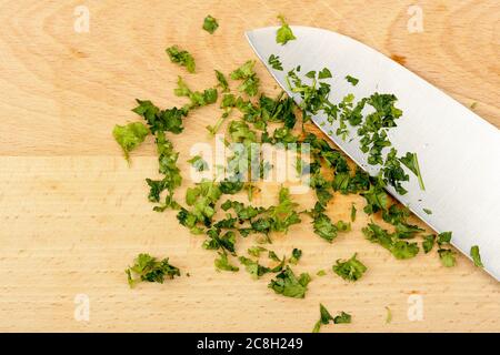 coltello e foglie di prezzemolo tritate sul tagliere Foto Stock