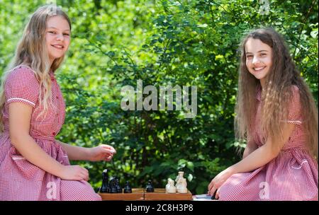 gioco di successo della competizione. due ragazze teen giocano a scacchi nel parco. giocatori di scacchi per bambini retrò. concetto di strategia. Strategia di pianificazione con figure di scacchi. Gioco di logica per lo sviluppo del cervello. Foto Stock