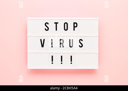 STOP VIRUS è scritto in lightbox su sfondo rosa. Concetto sanitario e medico. Vista dall'alto, spazio di copia. Concetto di quarantena. Foto Stock