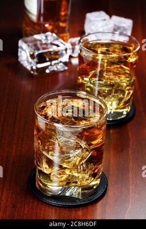 due bicchieri di whisky con ghiaccio su superficie di legno Foto Stock