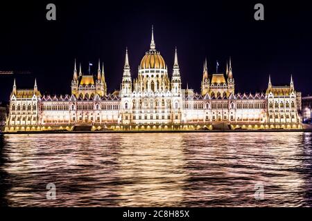 Il Parlamento di Budapest in Ungheria di notte, le riflessioni sul fiume Danubio acque. Foto Stock