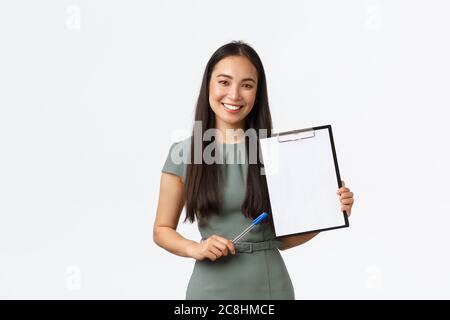 Sorridente attraente donna d'affari asiatica che mostra carte, esplane documento, mostrare appunti vuoti e utilizzare penna descrivere informazioni, in piedi bianco Foto Stock