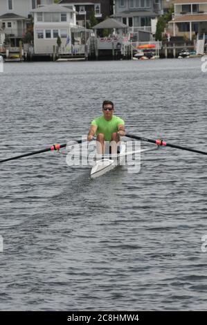 Vogatore e il suo singolo cranio che si dirige verso l'esterno per una fila sulla baia. Foto Stock