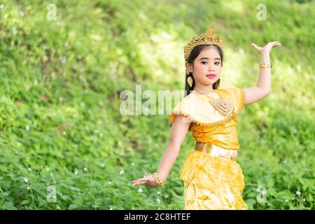 Un carino giovane studente asiatico della scuola elementare indossava un costume tradizionale tailandese dorato per eseguire la danza, che è una performance unica e famosa Foto Stock