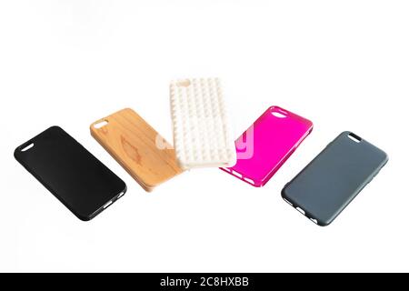 Pila di coperture posteriori in plastica multicolore per telefoni cellulari che si levitano su sfondo bianco. Scelta di accessori per custodia protettiva per smartphone. Foto Stock