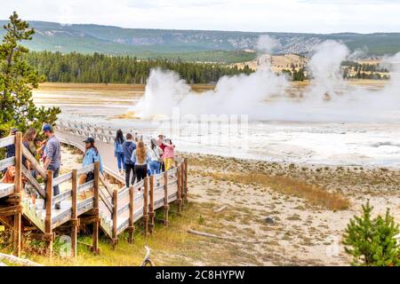 Wyoming, USA - 24 agosto 2019: I turisti visitano un geyser Clepsidra in eruzione nel bacino inferiore del Geyser del sentiero di pittura delle fontane a Yellowstone Natia Foto Stock