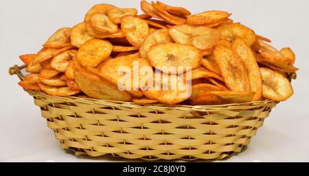 Chip di banana, fette di patate che si trasformano in patatine isolate, fette di kela croccanti, salate, masala (wafer), pomodoro, namkeen, patatine su ciotola dorata. Foto Stock