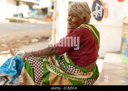 Chennai-Tamilnadu India , 24 luglio 2020. Vecchia donna seduta fuori dal negozio vicino alla strada Foto Stock