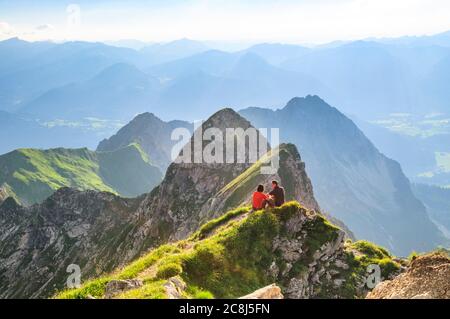 Gli escursionisti si siedono al sole sulla cima della montagna vicino a Nebelhorn, nella Allgäu bavarese Foto Stock