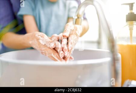 Bambini e adulti si lavano le mani. Protezione contro infezioni e virus. Primo piano. Foto Stock