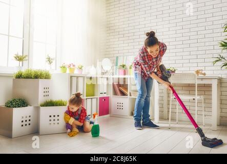 La famiglia è felice di pulire la camera. Madre e figlia fanno la pulizia in casa. Una giovane donna e una bambina spazzarono la polvere e aspirarono il Foto Stock