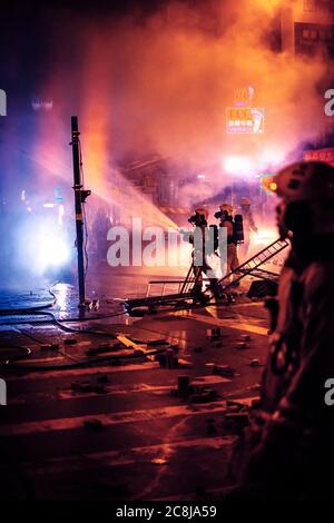 Hongkong - Novembre 2019: Il pompiere spegne il fuoco di una banca Citic cinese in fiamme durante l'Hong Kong 2019 Foto Stock