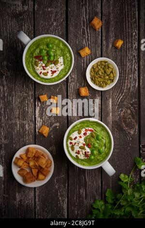 Zuppa di broccoli, verticale, spazio per la copia, vista dall'alto. Purea verde vegetale in due grandi tazze bianche. Dieta vegan zuppa di broccoli, zucchine, piselli verdi Foto Stock