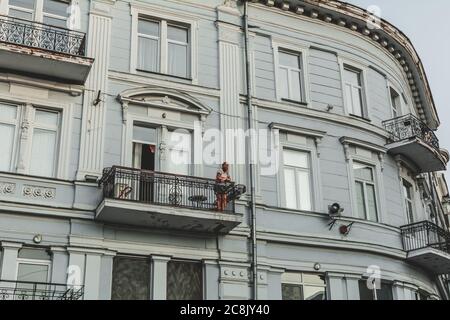 Ucraina, Odessa - 23 agosto 2019: Ragazza sul balcone di un edificio in stile neoclassicismo al tramonto. Foto Stock
