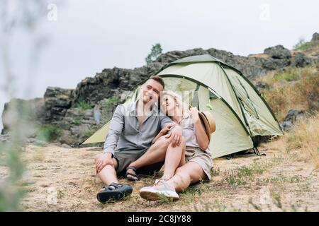 Felici giovani coppie viaggiatori in abiti casual messo tenda in montagna. Turismo locale, concetto di viaggio nel fine settimana Foto Stock