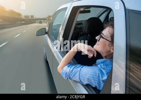 Donna passeggero seduto sul sedile posteriore e guardando fuori dal finestrino quando la sua auto guida autonoma si muove in autostrada. Foto Stock