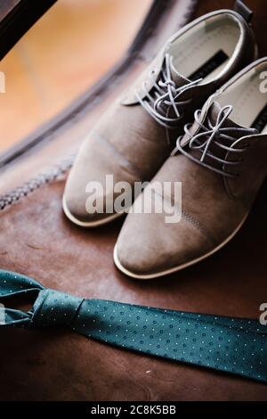 Cravatta verde scuro e scarpe marroni da uomo su sfondo marrone. Foto Stock