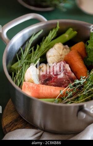 Ingredienti per cucinare brodo osseo. Brodo pentola con verdure, erbe e manzo. Orientamento verticale Foto Stock