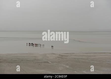 Un gruppo di persone che camminano in un fango, Mont st Michelle, Francia Foto Stock