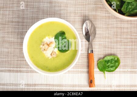 Zuppa di crema verde in un recipiente bianco con foglie di spinaci. La vista dall'alto. Foto Stock