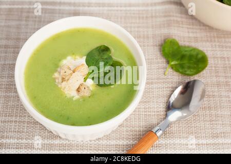 Zuppa di crema verde in un recipiente bianco con foglie di spinaci. La vista dall'alto. Foto Stock