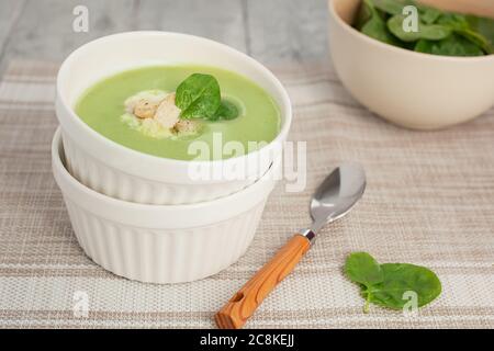 Zuppa di crema verde in un recipiente bianco con foglie di spinaci. La vista dall'alto. Foto Stock