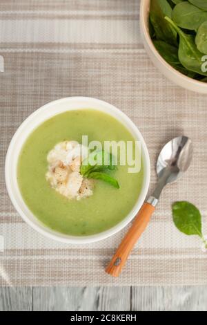 Zuppa di crema verde in un recipiente bianco con foglie di spinaci. La vista dall'alto. Foto Stock