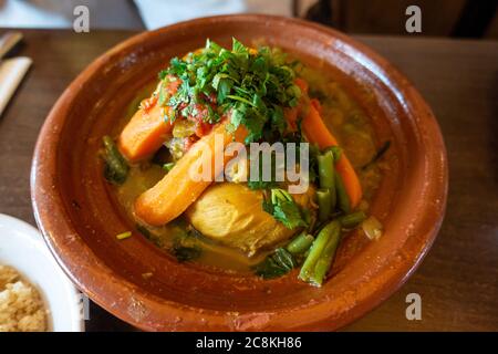 Tagine di pollo, piatto marocchino, con verdure servite in un ambiente rustico in ceramica. Foto Stock