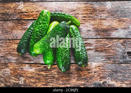 Cetrioli freschi e succosi verdi su un vecchio tavolo di legno Foto Stock