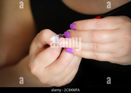 Donna che si fa manicure in casa pittura unghie con acquerello, visto solo le mani Foto Stock