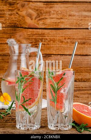 Acqua infusa di pompelmo con rosmarino su fondo di legno. Spazio di copia Foto Stock